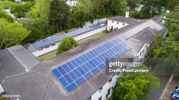 reihen von sonnenkollektoren auf dem dach des gebäudes - dachgiebel stock-fotos und bilder