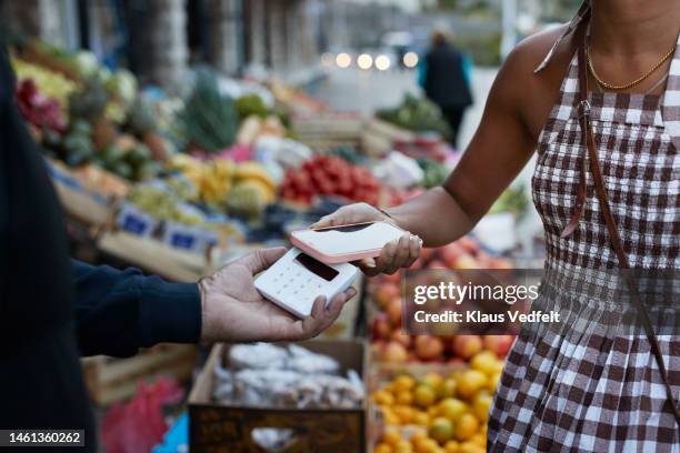 customer paying through smart phone at market - apple pay stock pictures, royalty-free photos & images