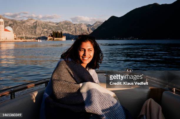 young woman looking away while sitting in motorboat - montenegro photos et images de collection