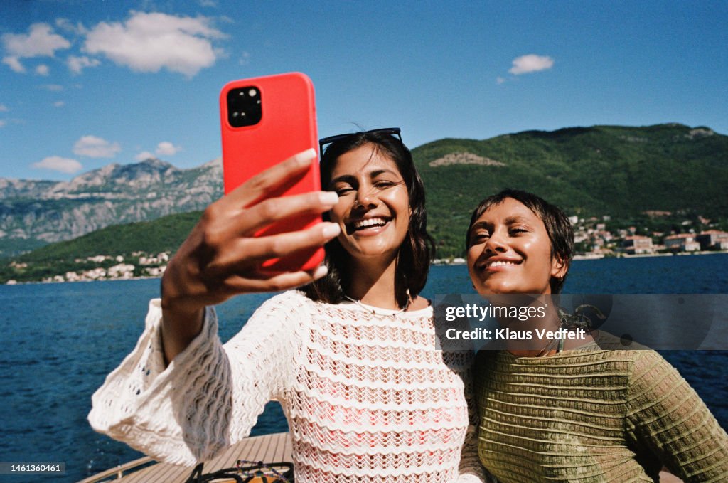 Woman taking selfie with female friend on smart phone