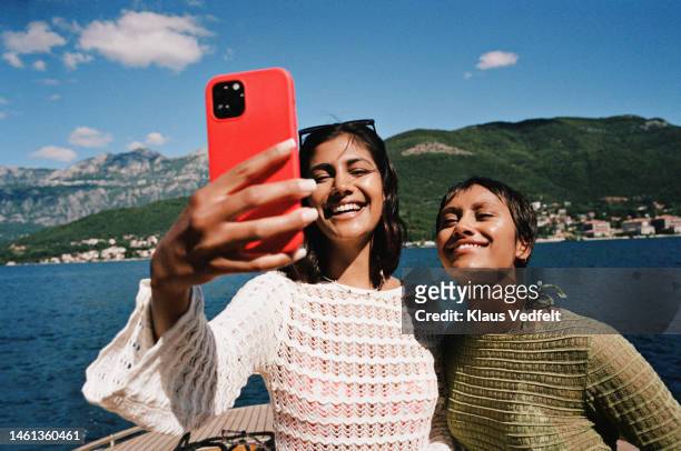 woman taking selfie with female friend on smart phone - telephone call holiday stock pictures, royalty-free photos & images