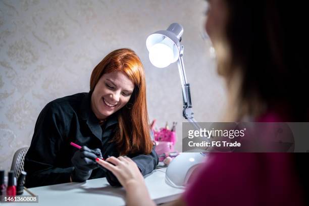 beautician doing manicure for a client at a beauty salon - gel effect stock pictures, royalty-free photos & images