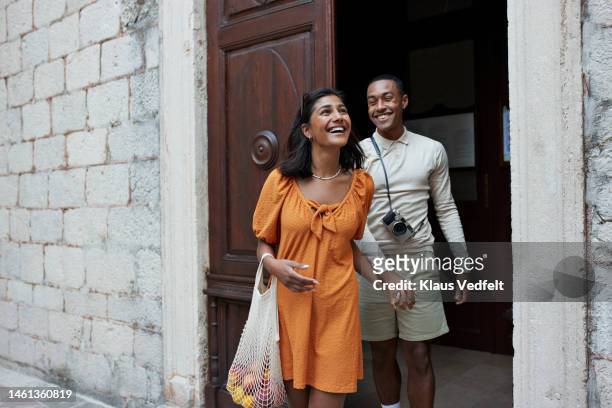 happy young couple walking out of doorway - travel stock-fotos und bilder