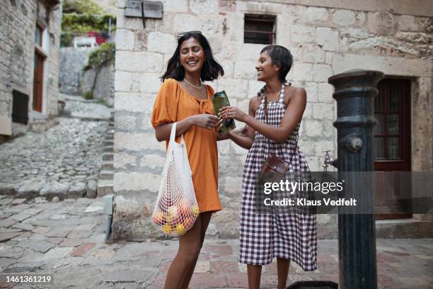 woman giving water bottle to female friend - drinking fountain stock pictures, royalty-free photos & images