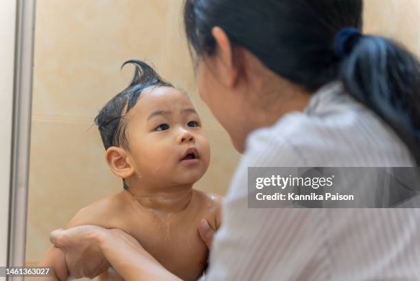 eltern waschen ein haar für ihr süßes kleinkind baby junge im badezimmer. süßes asiatisches neugeborenes, das beim baden genießt und entspannt. elternteil, der sich zu hause um das kind kümmert. familien-lebensstil elternverbindung liebevolles konze - kid bath mother stock-fotos und bilder