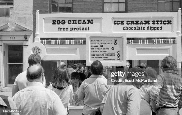 Pedestrians stop at an egg cream and ice cream stand on 9th Avenue in Hell's Kitchen during the International Food Festival, New York, New York, May...