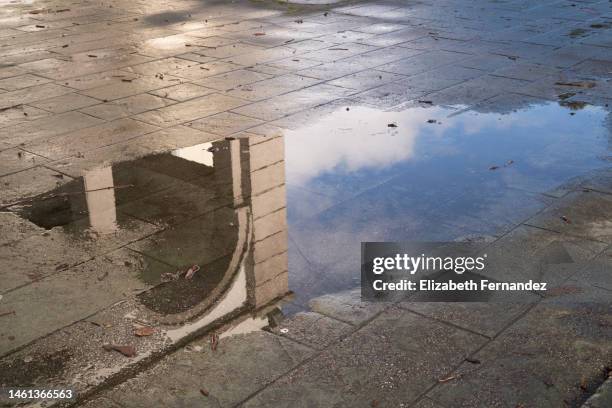 rainy day. reflection of the building in puddle on the city street during rain. - rain puddle stock pictures, royalty-free photos & images