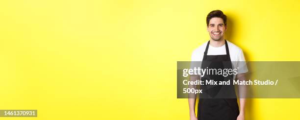 young man waiter in black apron,smiling,working in store or coffee - apron isolated stockfoto's en -beelden