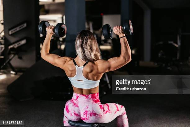 young woman training with dumbbells at the gym - images of female bodybuilders stock pictures, royalty-free photos & images