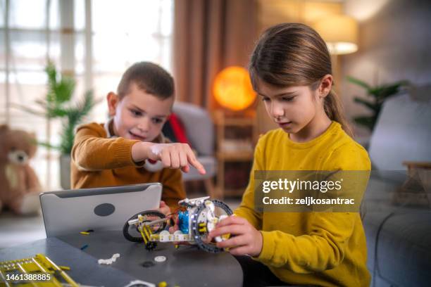 niños haciendo robot de bricolaje mirando desde una tableta digital en casa - genius fotografías e imágenes de stock