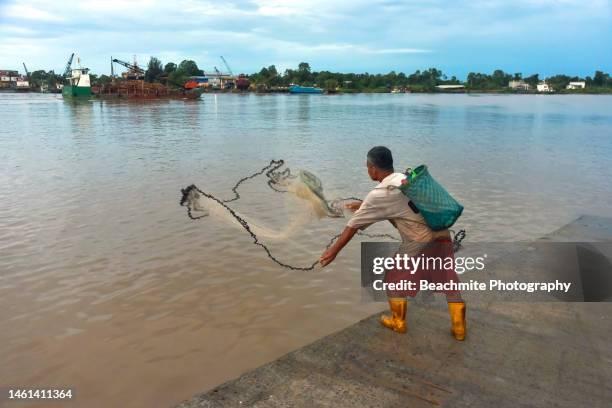 fisherman casting his net into the rajang river in sibu, sarawak, malaysia - sibu river stock pictures, royalty-free photos & images