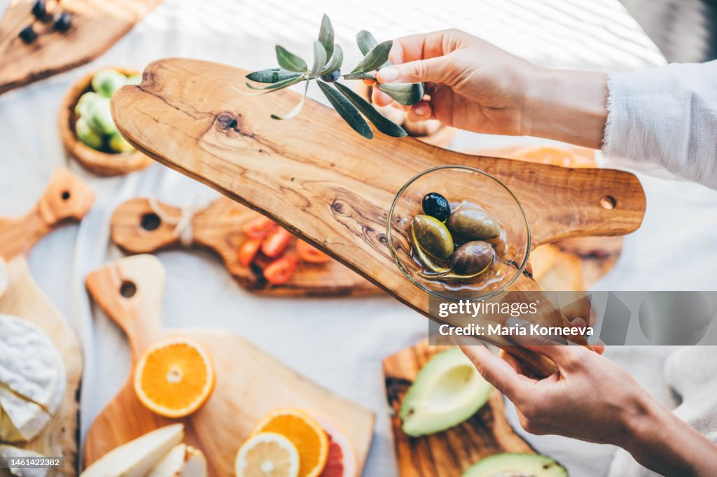 Olive branch and plate with olive on a olive wooden cutting board.