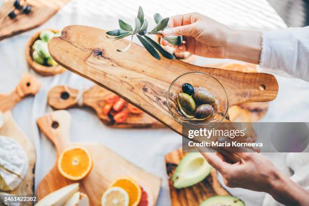 olive branch and plate with olive on a olive wooden cutting board. - oliva nera foto e immagini stock
