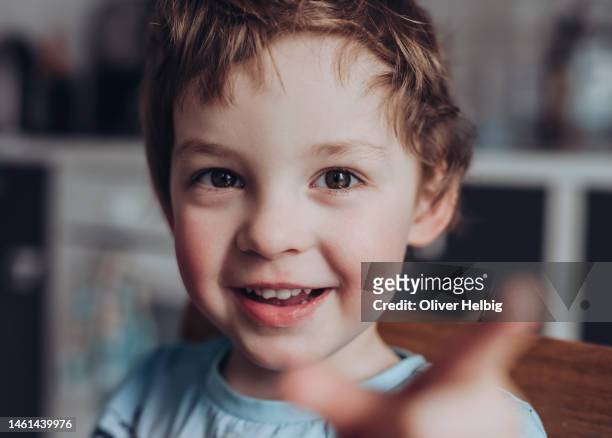 cute little boy kindergarten age smiles at camera and gestures with his hand - alleen jongens stockfoto's en -beelden