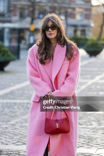 Julie Sergent Ferreri wears pink wool coat, red pants, heels, grey tights, skirt, blouse, sunglasses outside Lovechild 1979 during the Copenhagen...