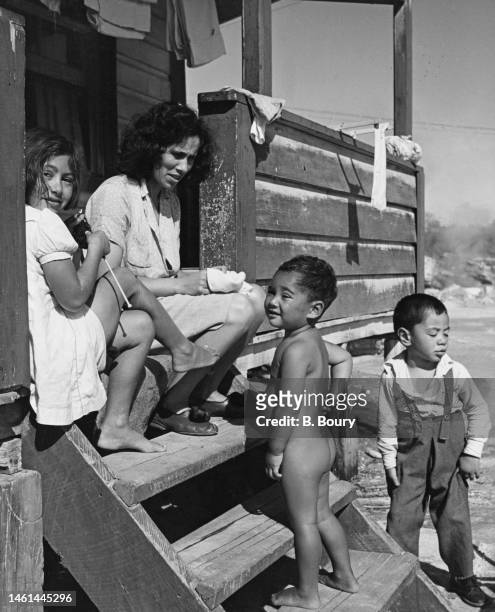Māori woman and children sitting on the steps of a house in Rotorua, New Zealand, circa 1955.
