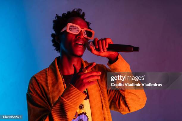 african american handsome young man singing into the microphone - hiphop stockfoto's en -beelden