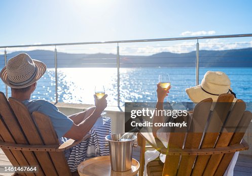 Couple relaxing and drinking wine on deck chairs in an over water bungalow. Couple relaxing and drinking wine on deck chairs in an over water bungalow.