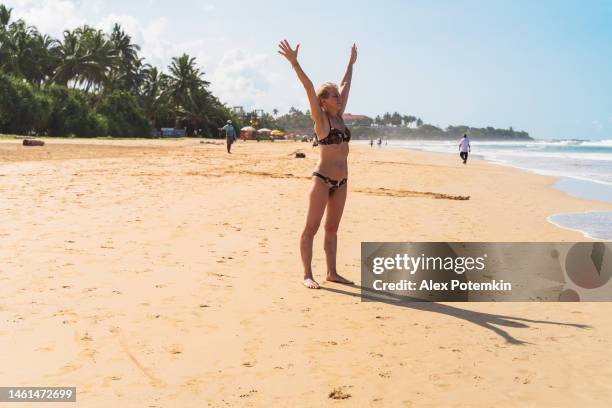 mujer europea mayor de 52 años, una viajera en solitario, haciendo práctica de yoga en una playa de arena tropical. - 50 54 years fotografías e imágenes de stock