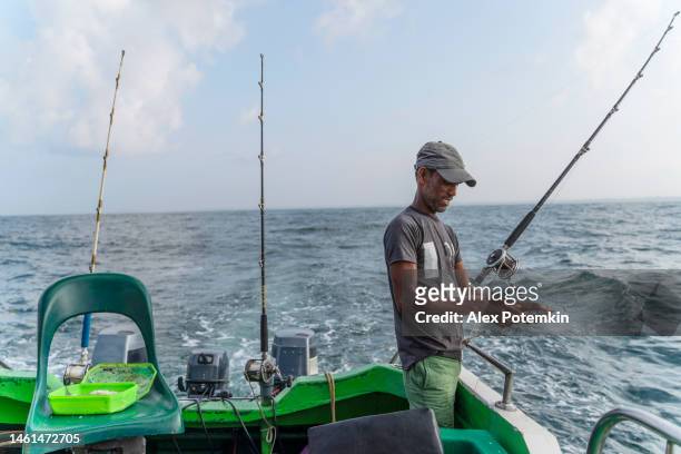 pescatore che alleva canne che si preparano per uno sport d'altura pesca nell'oceano, a bordo di una barca. - "alex potemkin" or "krakozawr" foto e immagini stock