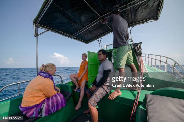i turisti, donne europee, riposano sotto la tenda e parlano con una guida locale e il capitano sul retro del peschereccio durante la battuta di pesca d'altura nell'oceano indiano, sulla costa dello sri lanka. - "alex potemkin" or "krakozawr" foto e immagini stock