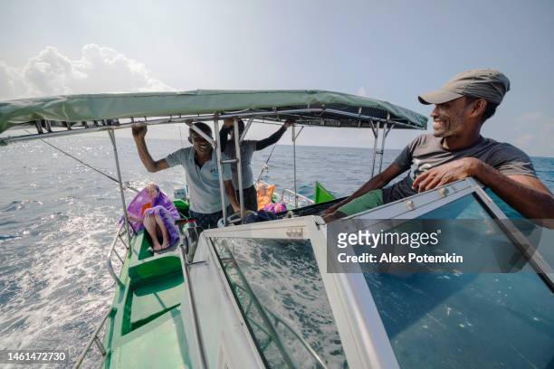 un capitano sta riposando in cima alla coperta di un piccolo peschereccio quando due pescatori, i membri dell'equipaggio, parlano con i turisti, le donne europee, che riposano sul retro in attesa di un boccone. - "alex potemkin" or "krakozawr" foto e immagini stock