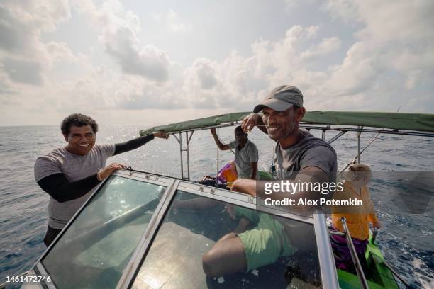 un capitano sta governando la barca quando due pescatori, membri dell'equipaggio, stanno parlando con i turisti, donne europee, che stanno riposando sul retro a bordo di un piccolo peschereccio durante la battuta di pesca d'altura. - "alex potemkin" or "krakozawr" foto e immagini stock