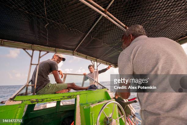 un capitano e due pescatori, i membri dell'equipaggio, stanno parlando a bordo di un piccolo peschereccio d'altura, su un ponte sotto una tenda. - "alex potemkin" or "krakozawr" foto e immagini stock