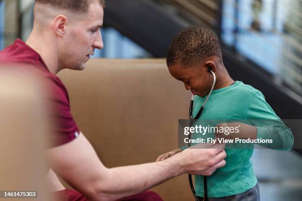 male caucasian nurse letting pediatric patient listen to his own heartbeat with a stethoscope - listening to heartbeat 個照片及圖片檔