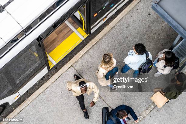 la gente se agolpa esperando el autobús de cercanías de la ciudad en la parada de transporte, vista superior - man riding bus fotografías e imágenes de stock