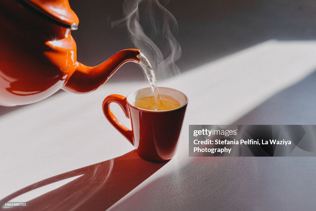 Enamel Teapot Pouring Tea in a Cup