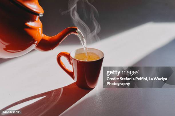 enamel teapot pouring tea in a cup - tea pot stock pictures, royalty-free photos & images