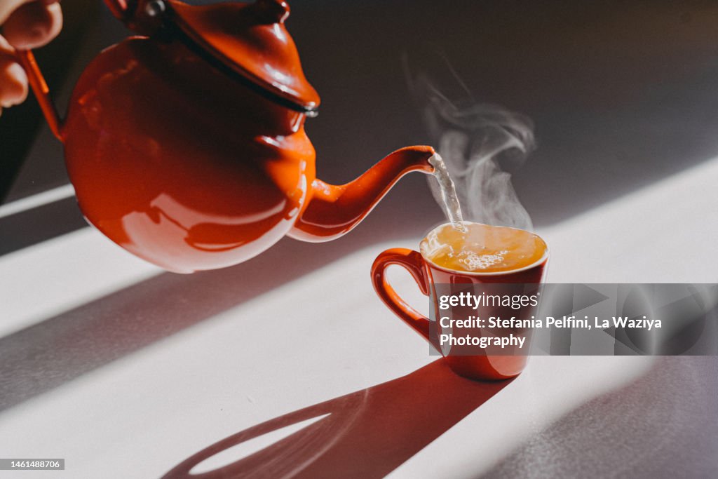 Enamel Teapot Pouring Tea in a Cup
