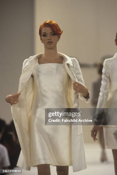 Model wearing a netural toned dress with matching coat from the Oscar de la Renta Spring 1996 runway show.