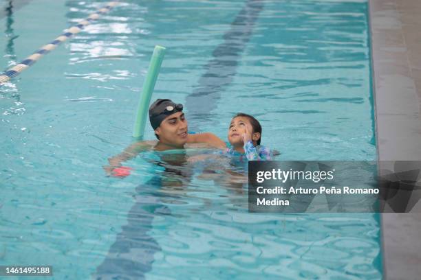 instructor helping a girl in the pool - swimming coach stock pictures, royalty-free photos & images