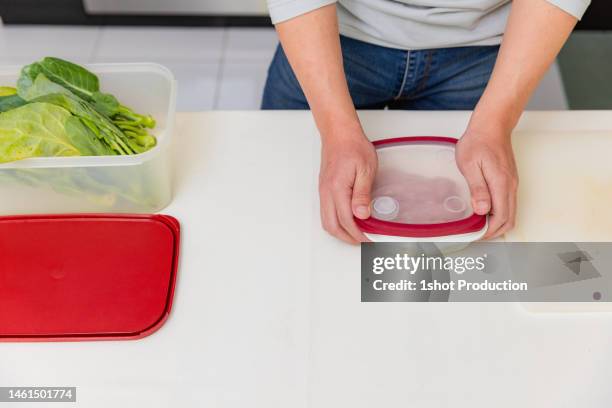 asian man putting raw chicken meat in food container in kitchen. - contamination stock pictures, royalty-free photos & images