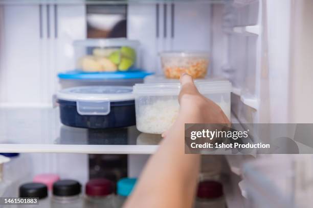 asian woman stored leftovers food in plastic container put into refrigerator. - leftover stockfoto's en -beelden