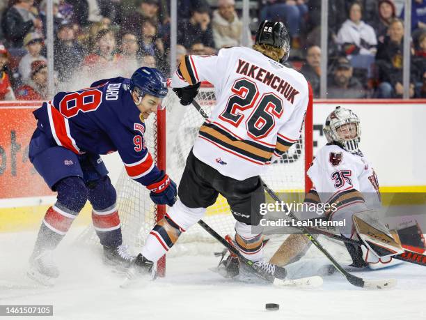 Conner Bedard of the Regina Pats takes a shot on Brayden Peters of the Calgary Hitmen and Carter Yakemchuk of the Calgary Hitmen at Scotiabank...