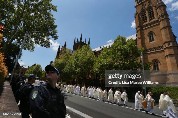 Members of the church form a procession to lead the hearse carrying Cardinal George Pell outside St. Mary’s Cathedral along College Street on...