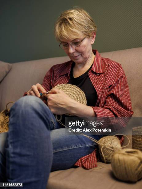 attraente donna matura di 54 anni che fa l'uncinetto, facendo un cesto di iuta fatto a mano. - "alex potemkin" or "krakozawr" foto e immagini stock