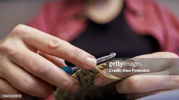 close-up hands of a mature woman doing crocheting, making a hand-made jute basket. - crochet stock pictures, royalty-free photos & images