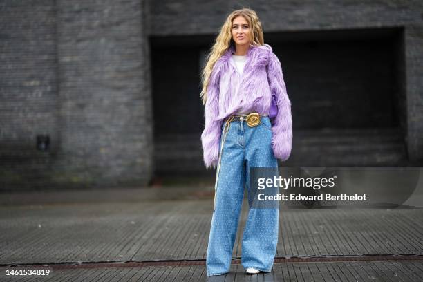 Emili Sindlev wears blue earrings, a pale purple large fluffy fur jacket, a white t-shirt, a purple shiny leather quilted Timeless handbag from...