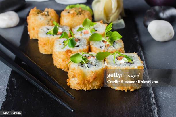 fried tempura sushi roll with salmon and cheese on black board. close-up. seafood concept - tempura stock pictures, royalty-free photos & images