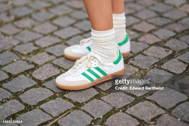 Emili Sindlev wears white socks, white shiny leather and green logo suede sneakers from Adidas , outside OperaSport , during the Copenhagen Fashion...