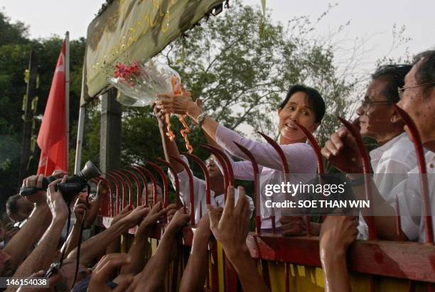 Myanmar's detained opposition leader Aung San Suu Kyi holds a bouquet of flowers as she appears at the gate of her house after her release in Yangon...