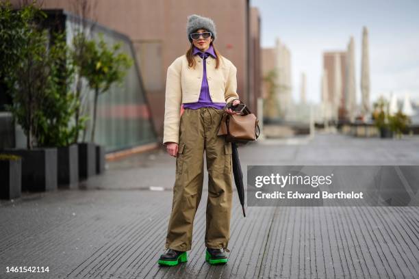 Guest wears a gray wool hat, pale blue sunglasses, silver earrings, a purple ribbed wool zipper high neck pullover, a pale yellow buttoned tweed...