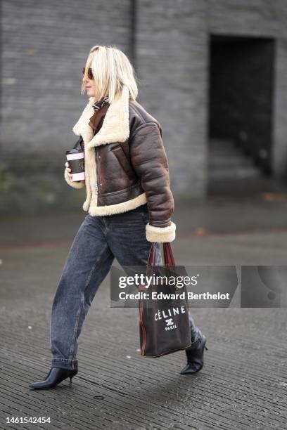 Guest wears brown sunglasses, white pearls pendant fringed earrings, a dark brown and white print pattern scarf, a black wool t-shirt, a dark brown...