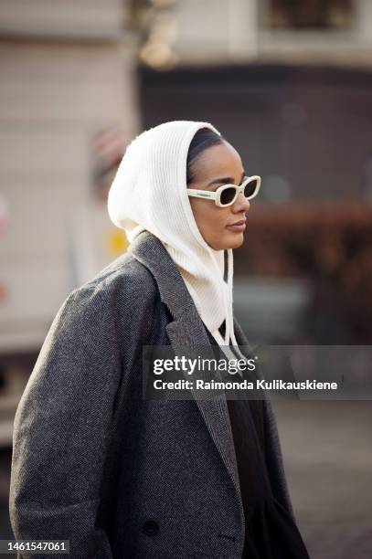 Guest wearing a grey coat, white balaclava, and white frame sunglasses outside Lovechild 1979 during the Copenhagen Fashion Week Autumn/Winter 2023...