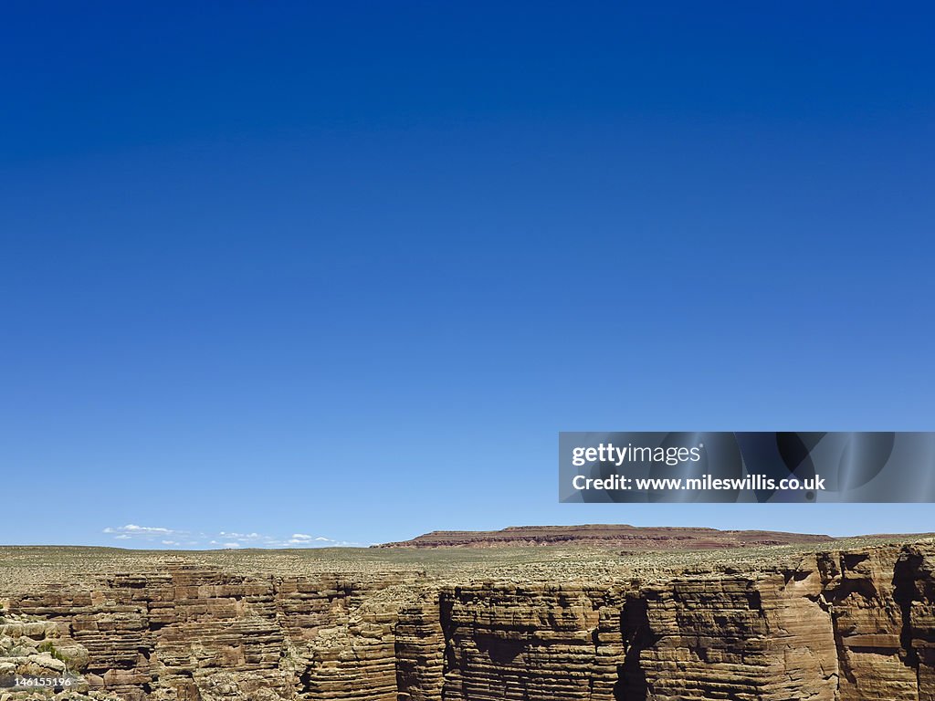 Rock layers below clear blue sky