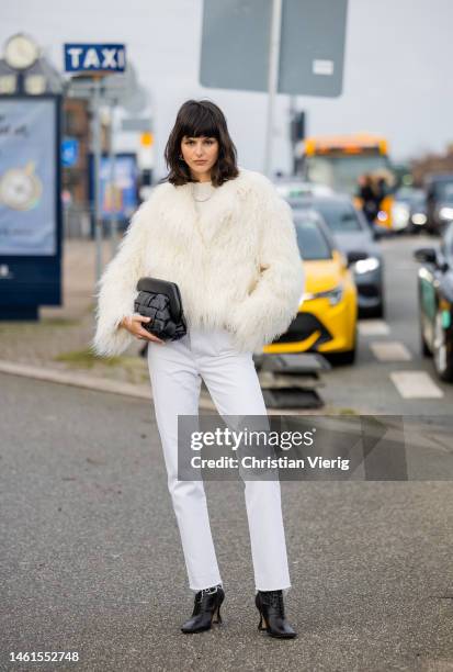 Justine Soranzo wears white faux fur jacket, pants, black clutch, ankle boots with heel outside OpéraSport during the Copenhagen Fashion Week...